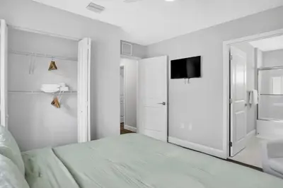 a white bedroom with a bed and a flat screen tv at Sistrunk Shades Villas Units #1 & #2 Combined in Fort Lauderdale