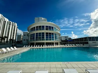 a building with a large swimming pool in front of it at Beachfront Property Pool Gym Tennis Miami Beach! in Miami Beach