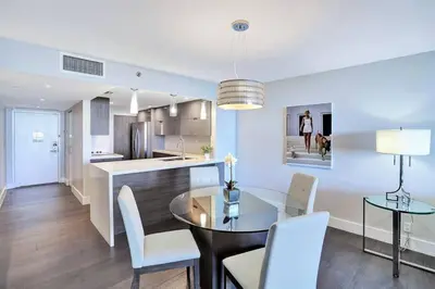 a dining room and kitchen with a glass table and chairs at Miami Vibes! Biscayne Bay Water and Park Views! in Miami