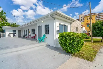a white house with a green chair in front of it at Lovely 1 Bedroom Walking Distance To Ocean - Suite 9 in Hollywood