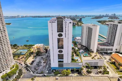 an aerial view of a tall white building next to the water at Calypso - Gorgeous Miami Renovated Spacious Condo! in Miami