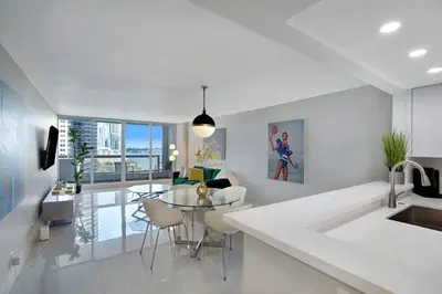 a white kitchen with a table and a dining room at Shock Wave! NEW Renovated Condo With Water Views! in Miami