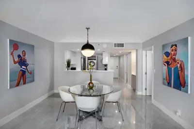 a dining room with a glass table and some paintings at Shock Wave! NEW Renovated Condo With Water Views! in Miami