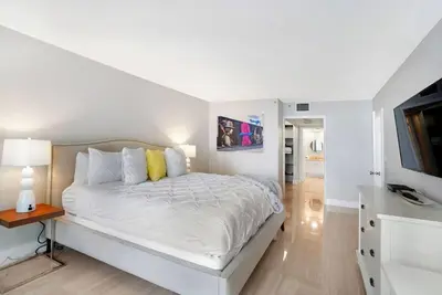 a white bedroom with a bed and a television at Endless Summer! Incredible Water Views in Miami