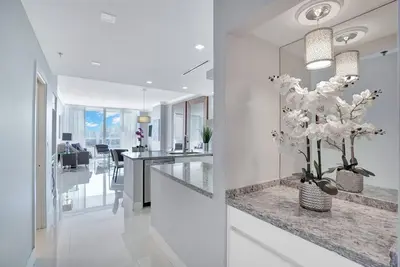 a white room with a counter with a vase of flowers at Sky High Penthouse! Water & City Views (top floor) in Miami
