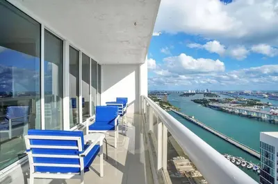 a balcony with blue chairs and a view of the water at Sky High Penthouse! Water & City Views (top floor) in Miami