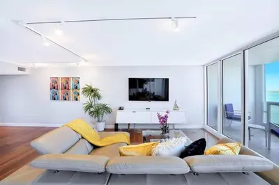 a living room with a white couch and a tv at Wait N' Sea! Direct Water Views, Steps From Pool! in Miami