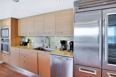a kitchen with stainless steel appliances and wooden cabinets at Wait N' Sea! Direct Water Views, Steps From Pool! in Miami