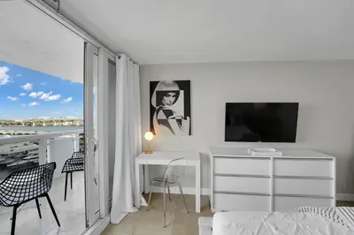 a bedroom with a desk and a tv and a balcony at Permanent Vacation! Direct Water Views! in Miami