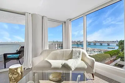 a living room with a couch and large windows at The Palms! Direct water view corner condo in Miami