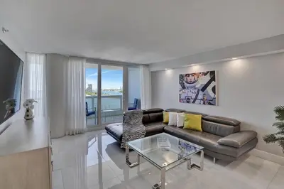 a living room with a couch and a glass table at A Wave From It All! Direct water views! in Miami