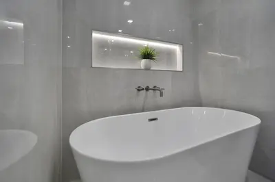 a bathroom with a white tub and a plant on the wall at A Wave From It All! Direct water views! in Miami