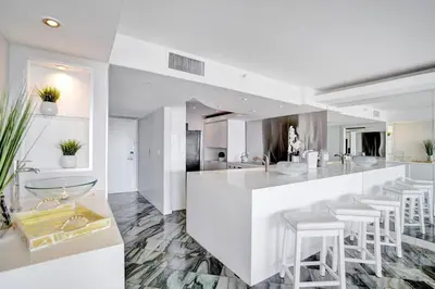a white kitchen with a bar with stools at Sea Forever! Miami Skyline And Water Views in Miami
