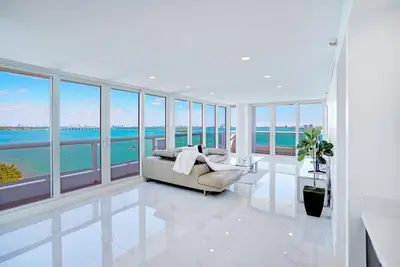 a living room with a couch and some windows at Feels Like Summer ~ Panoramic Water Views! in Miami