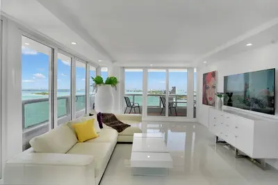 a white living room with a couch and a tv at Walking on Water! Water Views! in Miami