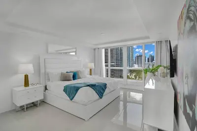 a white bedroom with a bed and a large window at Walking on Water! Water Views! in Miami