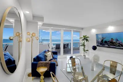 a living room with a blue couch and a mirror at Fantasy! Water & Park Views! in Miami
