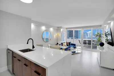 a white kitchen with a sink and a living room at Fantasy! Water & Park Views! in Miami