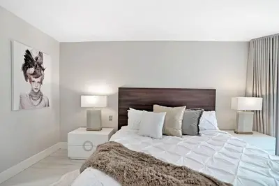a white bedroom with a large bed and two lamps at Sun-Kissed & Sunshine! Direct Water and City Views in Miami