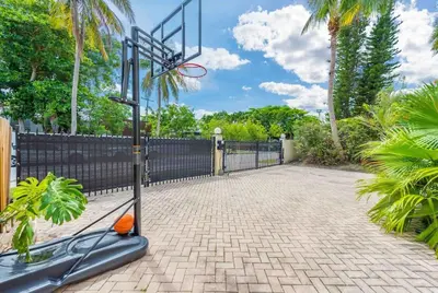 a basketball hoop in a driveway with a fence at Villa sleeps 18 in Miami Shores with Movie theater / Pool / Jacuzzi in Miami