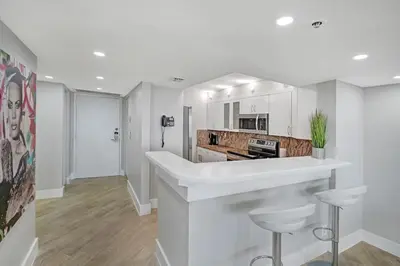 a white kitchen with a counter and stools at Over The Moon! Miami Skyline and Water Views! in Miami