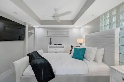 a white bedroom with a bed and a chair at Over The Moon! Miami Skyline and Water Views! in Miami