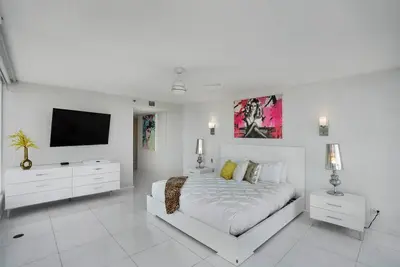 a white bedroom with a bed and a flat screen tv at Seas The Day! Complete Panoramic Water Views in Miami