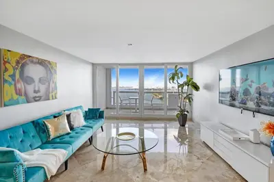 a living room with a blue couch and a glass table at First Class! - Crystal clear water views! in Miami