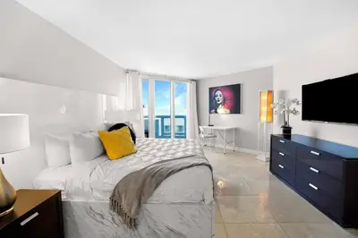 a white bedroom with a bed and a tv at Pisces Dream - Direct water views! in Miami