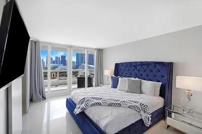 a bedroom with a blue bed and a large window at The Marilyn! Renovated and Amazing Skyline Views! in Miami