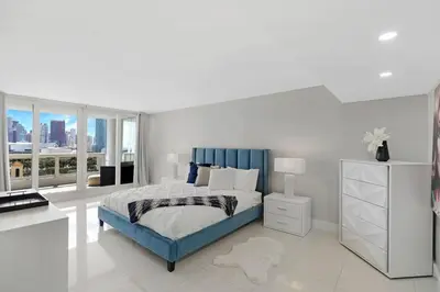 a white bedroom with a blue bed and a desk at The Marilyn! Renovated and Amazing Skyline Views! in Miami