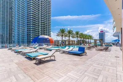 a swimming pool with chaise lounges and chairs on a building at HydeHotel 2BED Lux Condo Ocean View Resort in Hollywood