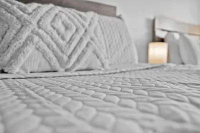 a close up of a bed with white sheets and pillows at Hollywood Beachfront Apartment in Hollywood