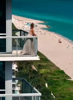 a woman walking on the balcony of a building near the beach at THE SETAI 5 STARS HOTEL-RESIDENCE MIAMI BEACH OCEANVIEW 2 Bedroom UNIQUE in Miami Beach