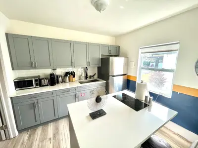 a kitchen with gray cabinets and a white table at Bahama Mama Las Olas and Holiday Park w Hot Tub in Fort Lauderdale