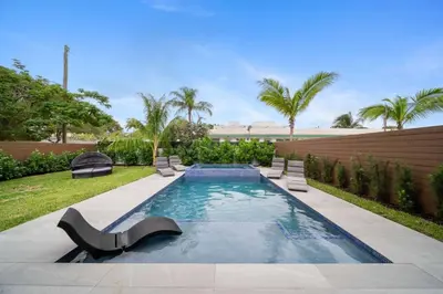 a swimming pool in a backyard with chairs and trees at The Elements Home with 2 Pools in Fort Lauderdale