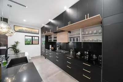 a kitchen with black cabinets and a sink at The Elements Home with 2 Pools in Fort Lauderdale