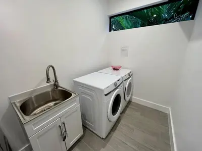 a kitchen with a washing machine and a sink at Botanical Oasis Home with 2 Pools in Fort Lauderdale