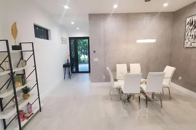 a dining room with a table and white chairs at Botanical Oasis Home with 2 Pools in Fort Lauderdale