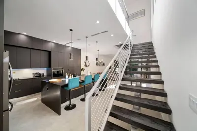 a staircase leading up to a kitchen with blue chairs at Las Olas Zen Home with Pool and Hot Tub Near Beach in Fort Lauderdale