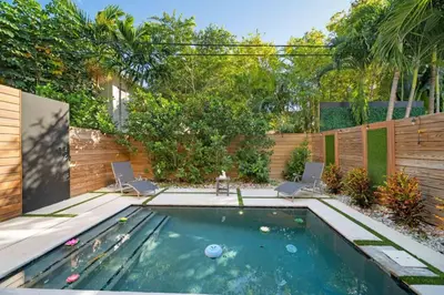 a swimming pool with two chairs in a backyard at Las Olas Zen Home with Pool and Hot Tub Near Beach in Fort Lauderdale