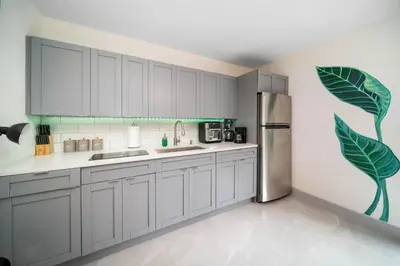 a kitchen with white cabinets and a stainless steel refrigerator at Newly Renovated Tropical Oasis Near Las Olas Beach in Fort Lauderdale
