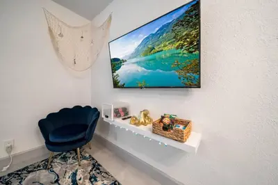 a room with a blue chair and a tv on a wall at Las Olas Newly Renovated Coastal 1BR Near Beach in Fort Lauderdale
