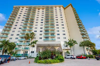 a large white building with palm trees in a parking lot at Ocean Reserve 1607 in Miami Beach