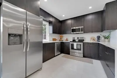 a kitchen with stainless steel appliances and wooden cabinets at Casa Copal: Relaxing Beach House in Hollywood