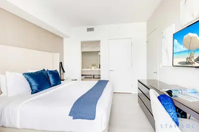 a white bedroom with a large bed with blue pillows at Luxury 1 Br Front Intracoastal View Balcony Pools in Hollywood