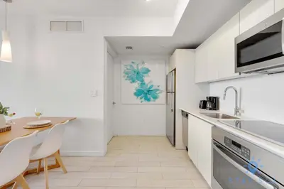 a kitchen with white cabinets and a table and chairs at Beachwalk Resort - Pool - Gym - Amazing view in Hallandale Beach