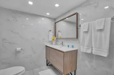a white bathroom with a sink and a mirror at Paradise Found! Miami Skyline and Water Views! in Miami