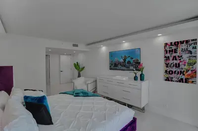 a white bedroom with a large bed and a dresser at Elevate! Water and Park Views in Miami