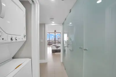 a white kitchen with a hallway leading to a living room at Iconic! Miami Skyline & Water Views in Miami